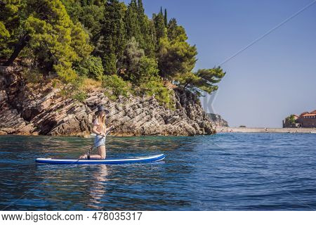 Young Women Having Fun Stand Up Paddling In Blue Water Sea Near St Stefan Island In Montenegro. Sup