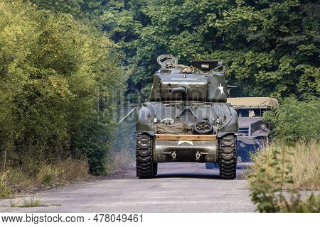 An American World War Ii Sherman Drives On The Road Between The Trees.