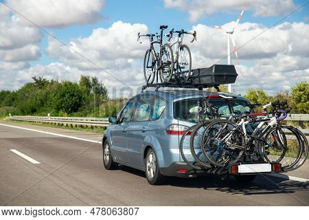 Back View Modern White Family Wagon Car With Mounted Roof Box Trunk And Bike Tail Carrier Driving Eu