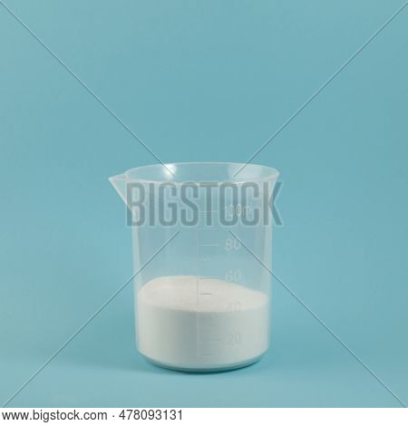 Succinic Acid Powder In Measuring Plastic Cup. Butanedioic Acid Or Spirit Of Amber. Food Additive E3