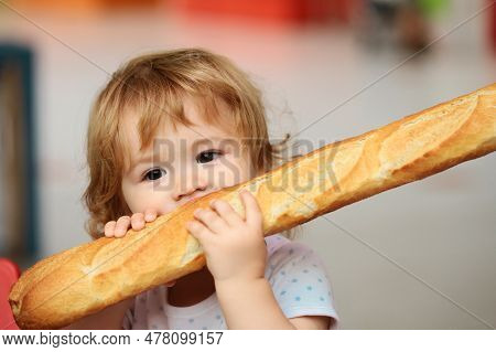 Cute Baby Eating French Baguette White Bread. Funny Toddler Child Eating Sandwich, Self Feeding Conc