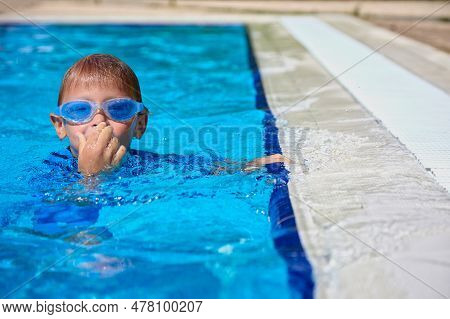 Happy Boy Diver Learns To Swim In The Pool. Water Activities Of The Child In The Summer In The Pool 