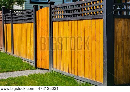 Nice New Wooden Fence Around House. Wooden Fence With With Wooden Gate With Green Lawn. Street Photo