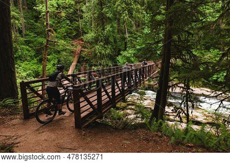 Tourists Crossing Wooden Bridge In Lacamas Park, Washington State. Picturesque Scene Of Outdoor Expl