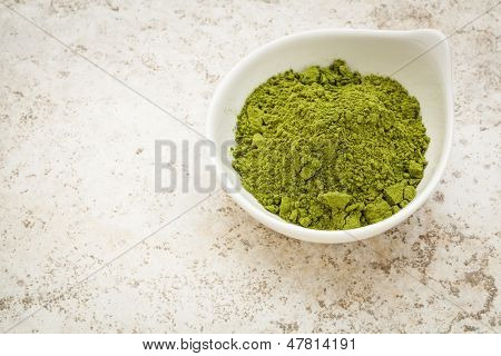 Moringa list prášek v malé misce proti keramické dlaždice pozadí