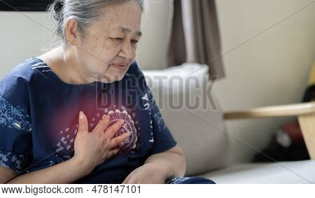 Senior Asian Woman Suffering From Chest Pain While Sitting On The Sofe At Home. Health Problems In O