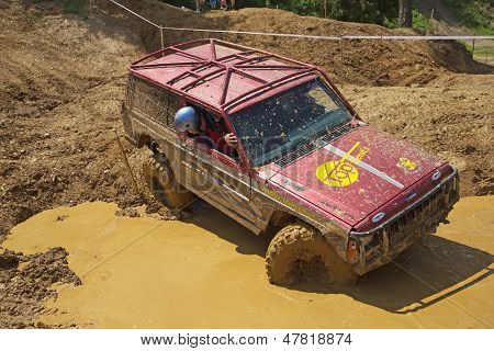 Rød Off Road bil passerer i Muddy Puddles
