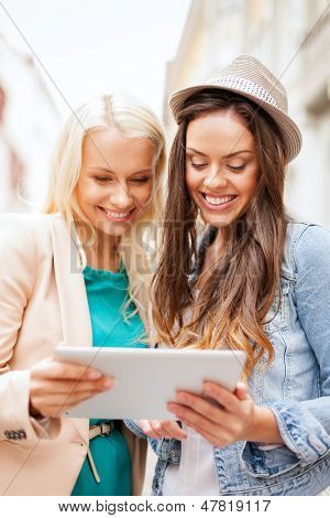 wakacje i turystyki pojęcia - piękne dziewczyny kwaterunku patrząc na tablet pc w mieście