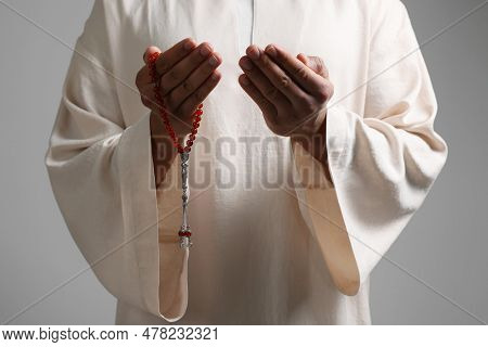 Muslim Woman With Misbaha Praying On Light Grey Background, Closeup