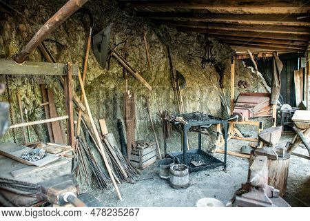View Of Traditional Blacksmiths Shop For Forging Medieval Iron, With Furnace And An Ancient Bellows 