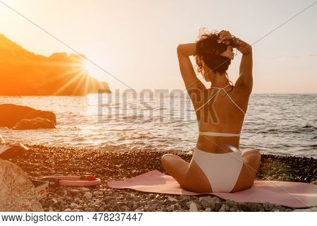 Woman Sea Yoga. Happy Woman In White Swimsuit And Boho Style Braclets Practicing Outdoors On Yoga Ma