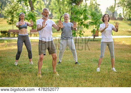 A Group Of People Practicing Qigong In A Park