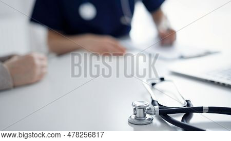 Stethoscope Lying On The Tablet Computer In Front Of A Doctor And Patient At The Background. Medicin