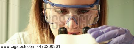 Woman Scientist Chemist In Protective Glasses Looking Through Microscope In Chemical Lab. Laboratory