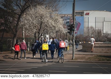 Bucharest, Romania - March 16, 2023: Glovo Ad Tazz Logos On The Bags Of Two Delivery Men On Bicycles