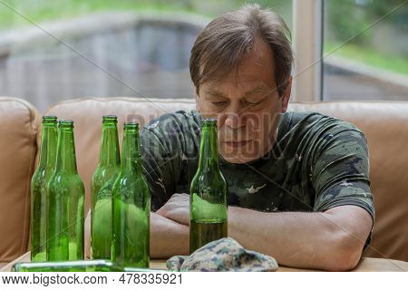 Elderly Man In Military Uniform Drinking Beer, Lots Of Empty Bottles, Neutral Background. Concept: W