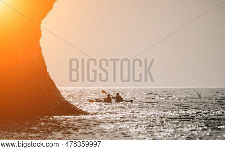 Happy Couple Kayaks In An Inflatable Kayak On The Sea At Sunset. Couple Kanoeing In The Sea Near The