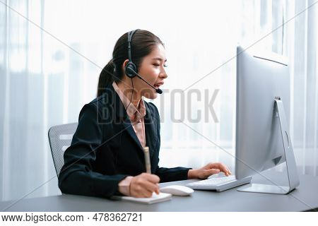Asian Call Center With Headset And Microphone Working On Her Laptop. Female Operator Provide Excepti