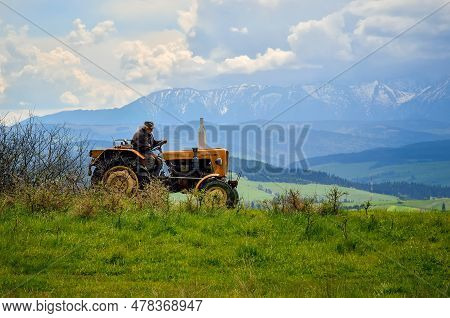 Pieniny Mountains, Poland - May 11, 2016: The Old Man Working On A Tractor In The Countryside In Pie
