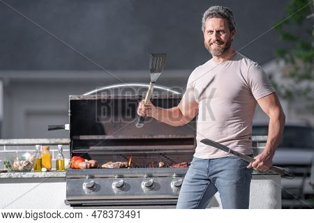 Man At A Barbecue Grill. Male Cook Preparing Barbecue Outdoors. Bbq Meat, Grill For Picnic. Roasted 