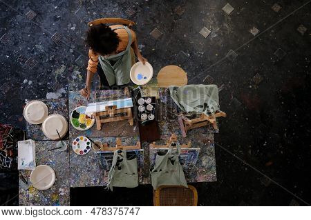 Aerial View Of Skilled Female Student Painting Picture On Canvas In Dark Creative Studio. Art, Educa
