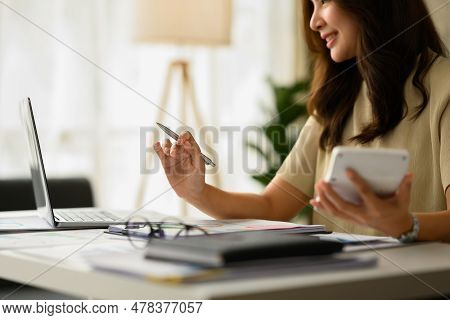 Businesswoman Working On Corporate Project Strategy Or Marketing Plan, Using Calculator At Desk