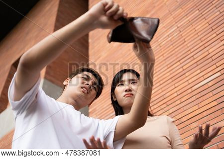 A Desperate Asian Opening Wallet And Looks At His Empty Wallet. Unhappy Asian People With No Cash In