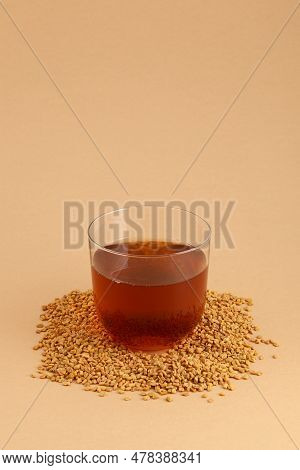 Glass Of Egyptian Fenugreek Yellow Tea, Helba Or Methi Dana Drink And Fenugreek Seeds On Beige Backg