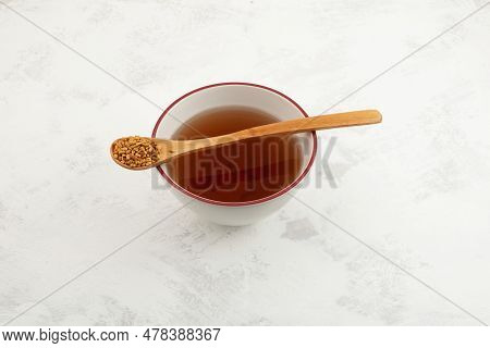 Fenugreek Seeds In Wooden Spoon And Methi Dana Drink In Tea Bowl. Helpful In Weight Loss, Digestion 