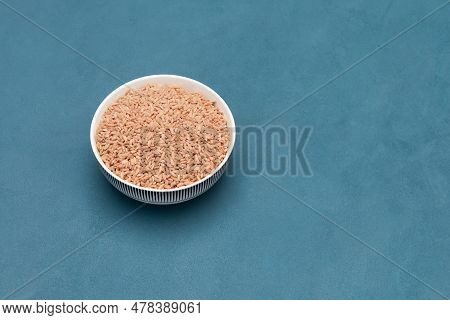 Pink Oriental Devzira Rice For Pilaf In Bowl. Selective Focus, Blue Background, Copy Space.