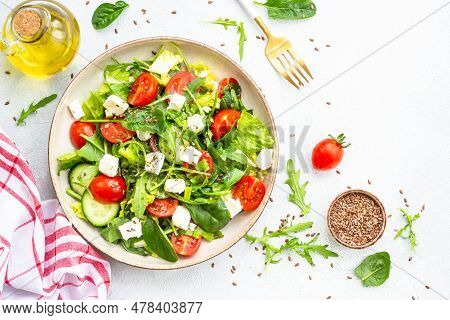 Spring Salad In Craft Plate. Spinach, Arugula, Tomatoes And Feta With Olive Oil. Top View On White.