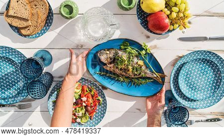 Gilt-head Bream Also Known As Orata Grilled On A Barbeque Grill Served By A Woman On A White Wooden 