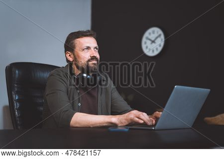 Worker Daydreaming While Sitting In Office. Man Dressed In Casual Wear, Typing On Laptop. However, D