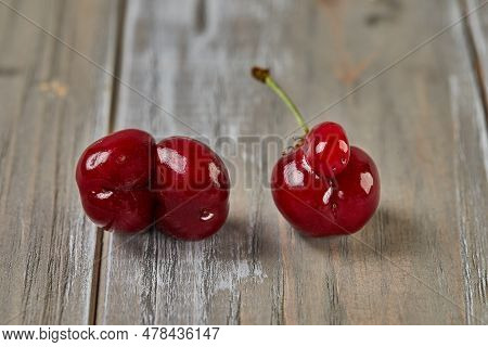 Natures Oddity: Ugly, Irregularly Shaped Cherry Stands Out Against A Rustic Wooden Backdrop