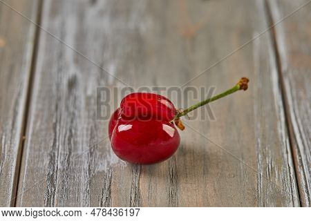 Natures Oddity: Ugly, Irregularly Shaped Cherry Stands Out Against A Rustic Wooden Backdrop