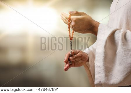 Muslim Man With Misbaha Praying On Blurred Background, Closeup. Space For Text