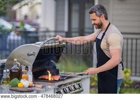 Hispanic Man Cooking On Barbecue In The Backyard. Chef Preparing Barbecue. Barbecue Chef Master. Man
