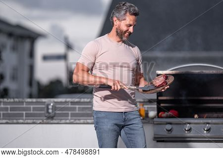 Man At A Barbecue Grill. Male Cook Preparing Barbecue Outdoors. Bbq Meat, Grill For Picnic. Roasted 