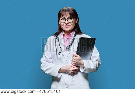 Wman Doctor Holding Laptop Looking At Camera On Blue Background