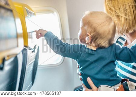 Mom And Child Flying By Plane. Mother Holding And Playing With Her Infant Baby Boy Child In Her Lap 
