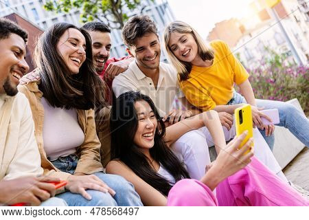 Young Group Of Gen Z People Having Fun Using Cell Phone Together Outside. Cheerful Community Of Stud