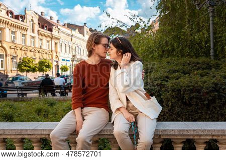 Young Caucasian Couple Relax In Park Sitting On Ballustrade. Romantic Date In Valentine's Day.