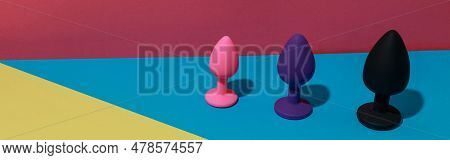 Different Buttplugs And Dildos For Anal Sex On Colored Background With Shadows. Sex Shop Concept