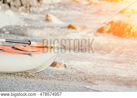 Happy Couple Kayaks In An Inflatable Kayak On The Sea At Sunset. Couple Kanoeing In The Sea Near The
