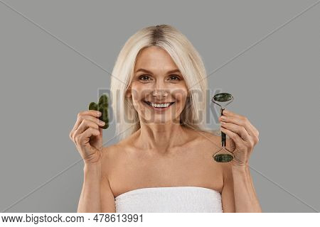 Beauty Tools. Mature Woman Holding Jade Guasha Stone Scraper And Greenstone Roller