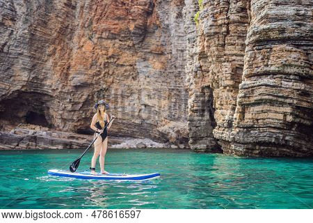 Young Women Having Fun Stand Up Paddling In Blue Water Seaamong The Rocks In Montenegro. Sup