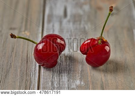 Natures Oddity: Ugly, Irregularly Shaped Cherry Stands Out Against A Rustic Wooden Backdrop