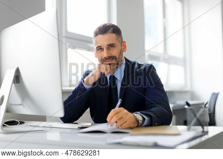 Portrait Of Happy Middle Aged Man Entrepreneur Working On Computer And Taking Notes, Sitting At Work