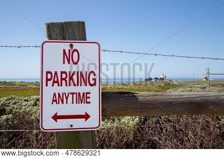 No Parking Anytime Sign On The Fence With Barbed Wire. No Parking Anytime Sign With Oceanfront Light