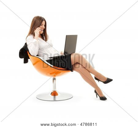 Empresaria en silla con ordenador portátil y teléfono